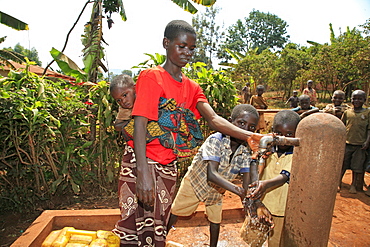 Burundi woman and her sons collecting water from a public stand pipe which is situated 300 metres from her house. Gitera.