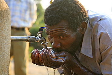 Burundi man drinking water from a standpipe, gitera.