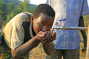 Burundi woman drinking water from a standpipe, gitera.