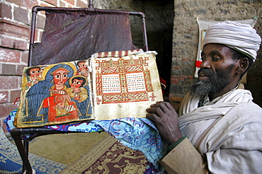 Religion, ethiopia. NaâˆšÂ¢Â¬Ã„Â¬Ã´akuto laâˆšÂ¢Â¬Ã„Â¬Ã´ab church, 7 kms from lalibela, built in a cave. The priest showing some of the churchâˆšÂ¢Â¬Ã„Â¬Ã´s treasures: with a manuscript book depicting the miracles of mary