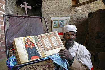 Religion, ethiopia. NaâˆšÂ¢Â¬Ã„Â¬Ã´akuto laâˆšÂ¢Â¬Ã„Â¬Ã´ab church, 7 kms from lalibela, built in a cave. The priest showing some of the churchâˆšÂ¢Â¬Ã„Â¬Ã´s treasures: with a manuscript book depicting the miracles of mary