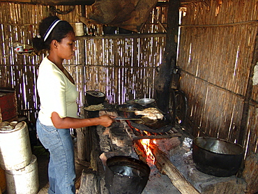 Colombia jasmine abufe grilling fish on a woodstove in her house beside the rio magdalena, barrancabermeja