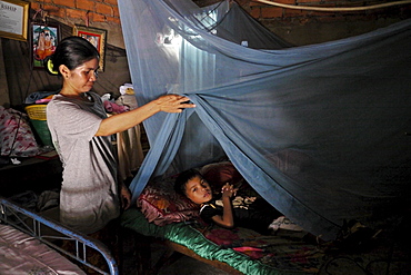 CAMBODIA 8-year-old Khoeun Sovan in bed under mosquito net, Mean Caeay slum, Phnom Penh