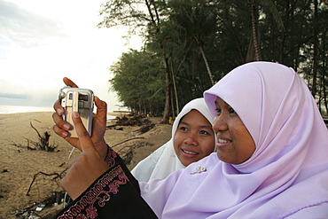 Thailand moslem girls with digital camera, songkhla beach photo sean sprague 2005