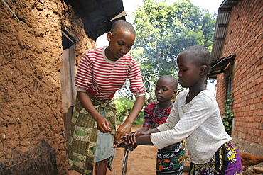 Tanzanian sisters washing their hands at the family tap. Mvango village, same, in the north-east near kilimanjaro