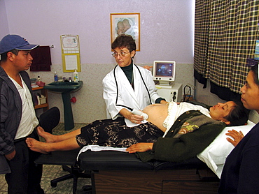 Guatemala gynacologist joanna bruno examining a mayan indian woman and her baby while the husband looks on. Clinic of santa clara la laguna