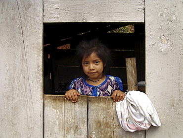 Honduras girl looking out from a window of her house. Village near marcala