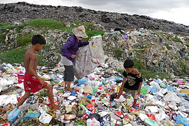 CAMBODIA Scavenger Soun Srey Thouch searching for recyclable materials on Phnom Penh's Mean Caeay garbage dump, with sons Khoeun Sovan (8) and Khoeun Sanja (10)