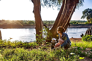 A young woman observes the early morning light while camping in Samburu National Park, Kenya, East Africa, Africa