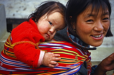 Bhutanese mother uses traditional kira to carry child