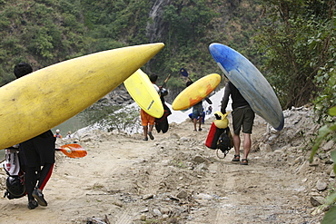 Paddlers carry their kayak to the start point for Downriver challenge. Paddlers race from a Le Mans style mass start, head to head down a stretch of challenging class 4 whitewater. Trisuli, Nepal