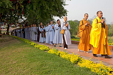 Buddhist pilgrims circumambulate the mayadevi temple and the pond in front of it. Lumbini, nepal