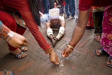 Some religious people reach Brahmayani temple measuring their body length. To do so, a person prostrates on the ground and extends his clasped hands above his head. An assistant puts a few grains of rice at the end of the clasped hands as a marking point. Then, the man steps to this marking point and then prostrates again. Bhaktapur, Nepal