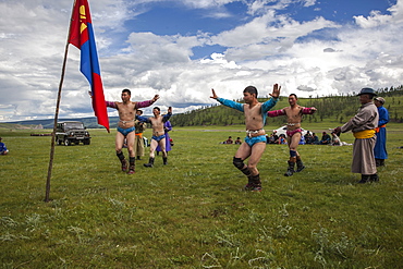 The wrestlers display their strong physique in a warm up Eagle Dance whilst their coaches announce their heroic deeds, Bunkhan, Bulgam, Mongolia, Central Asia, Asia