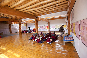 A light-filled elementary classroom. A white ceiling reflects light from the windows above. Traditional building methods and materials, such as the poplar and willow ceilings are combined with modern solar and passive solar technology. Druk Padma Karpo Institute. Shey, Ladakh, India