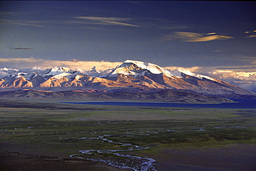 Gurla mandata. Tibet. barkha plain stretches as clouds light gather above bonpo mountain tagri trawo, tiger-striped mountain, known on english maps by sanskrit name, gurla mandhata with rakshas glittering beyond expanse of pilgrim tents