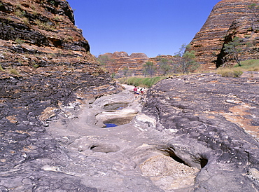 Tourists cross flood scoured rocks, past typical formations, Purnululu National Park, UNESCO World Heritage Site, Bungle Bungle, Kimberley, Western Australia, Australia, Pacific