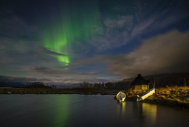 Aurora borealis over lake with boats and Kota, Kilpisjarvi, Northwest Finland, Lapland, Finland, Scandinavia, Europe