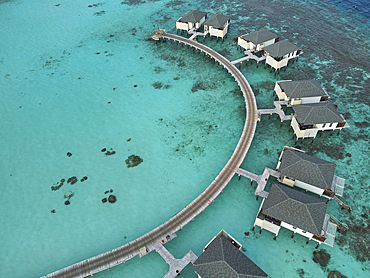 Water villas stand in a shallow lagoon close to the shore of a tropical paradise island in the Maldives: Havodda Island, Gaafu Dhaalu atoll, in the Maldives' far south, in the Indian Ocean.