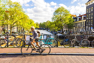 Cyclist riding over a bridge over Prinsengracht Canal, Amsterdam, Netherlands, Europe