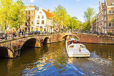 A boat going under a bridge over the Keizersgracht Canal, Amsterdam, Netherlands, Europe