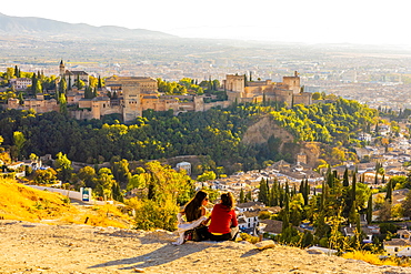 Two women looking at view of Alhambra and Sierra Nevada mountains, Granada, Andalucia, Spain, Europe