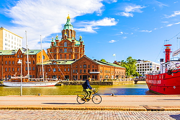 Uspenski Cathedral and cyclist by harbor in Helsinki, Uusimaa, Finland, Europe