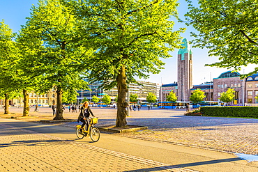 Young woman cycling by Helsinki Train Station in Helsinki, Uusimaa, Finland, Europe