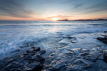 Dunstanburgh Castle at sunrise, seen from Embleton Bay, Northumberland, England, United Kingdom, Europe