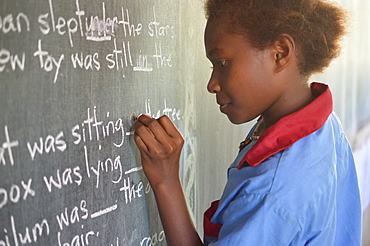 Young girl completing a gap filling exercise on a chalkboard at Malasang Primary School, Buka, Bougainville, Papua New Guinea, Pacific