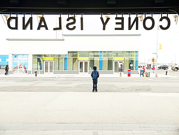 A schoolboy waits to cross the road outside Coney Island subway station, New York, United States of America, North America