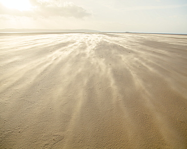 Shifting sands creating a cloud underfoot as wind whistles across the beach, West Kirkby, Wirral, England, United Kingdom, Europe