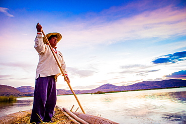 Quechua man rowing a boat on the Floating Grass islands of Uros, Lake Titicaca, Peru, South America