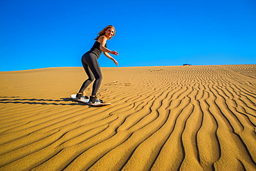 Woman sand boarding on sand dune, Huacachina Oasis, Peru, South America