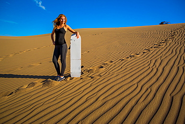 Woman sand boarding on sand dune, Huacachina Oasis, Peru, South America