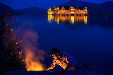 Boy cooking at twilight by the Jal Mahal Floating Lake Palace, Jaipur, Rajasthan, India, Asia