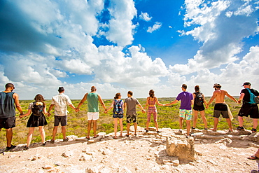 Group of people hold hands at the summit of Nohoch Mul Pyramid in the Ancient Mayan City of Coba, outside Tulum, Mexico, North America