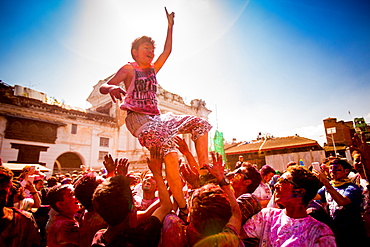 Boy being thrown in the air during the Holi Pigment Throwing festival in Durbar Square, Kathmandu, Nepal, Asia