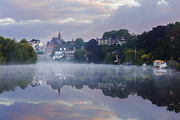 Early morning mist settles on the River Dee with boats and buildings reflected in the still water, Chester, Cheshire, England, United Kingdom, Europe