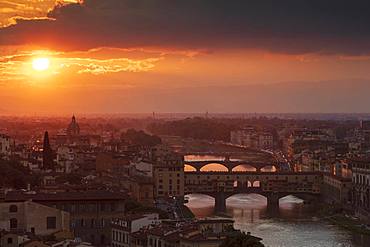 Sun setting behind the city of Florence with the Ponte Vecchio and Ponte Santa Trinita bridges over the Arno River, Florence, Tuscany, Italy, Europe