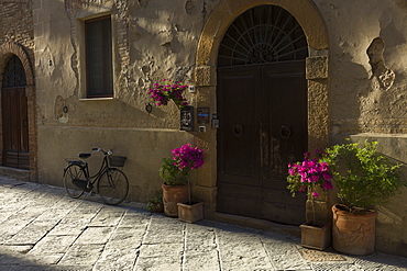 A bicycle and flowers outside a building in Pienza, Val D'Orcia, Tuscany, Italy, Europe