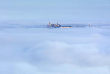 Pienza's Clock Tower and Cathedral Bell Tower rise above the clouds and fog that covers the Val d'Orcia below, UNESCO World Heritage Site, Tuscany, Italy, Europe