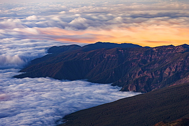 Clouds obscure the coastal villages below the dark volcanic mountains of Tenerife's north east coast at sunset, Canary Islands, Spain, Atlantic Ocean, Europe