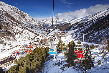 Looking down on the village of Obergurgl sat at the top of the Otztal valley as skiers ascend the mountain on chairlifts, Tyrol, Austrian Alps, Austria, Europe