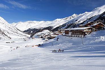 Groups of skiers enjoying the winter conditions with the village of Obergurgl and Otztal Alps beyond, Tyrol, Austria, Europe