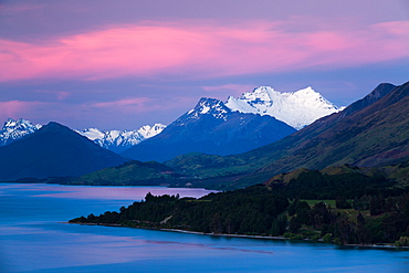 Snow covered Mount Earnslaw within New Zealand's Southern Alps set against a pink early evening sky beyond Lake Wakatipu, Otago, South Island, New Zealand, Pacific