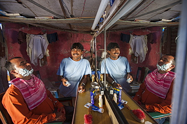 A hairdresser smiles for the camera in his little barbershop in Rishikesh, Uttaranchal, India, Asia