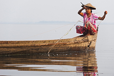 A young woman pulls in her nets at the end of the day on Indawgyi Lake, Kachin State, Myanmar (Burma), Asia