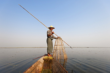 A basket fisherman after having trapped the fish in the basket will use the long spike to surround the fish with the net, Shan State, Myanmar (Burma), Asia