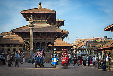 A group of tourists sit with their scooters in the historical temple square in Patan, Kathmandu, Nepal, Asia